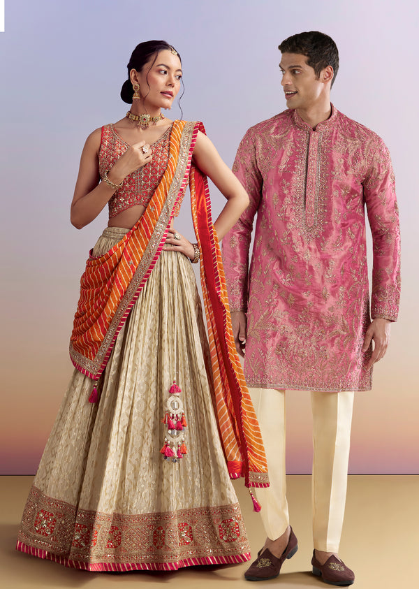 Festive Wedding Couple Set – Orange Brocade Bridesmaid Lehenga with Leheriya Dupatta for Her And Pink Embellished Tissue Kurta Set for Him