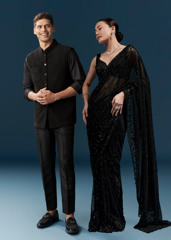 Bold Evening Couple Set – Black Heavy Embroidered Net Saree With Cutwork Border For Her And Black Embroidered Corduroy Shirt Jacket For Him